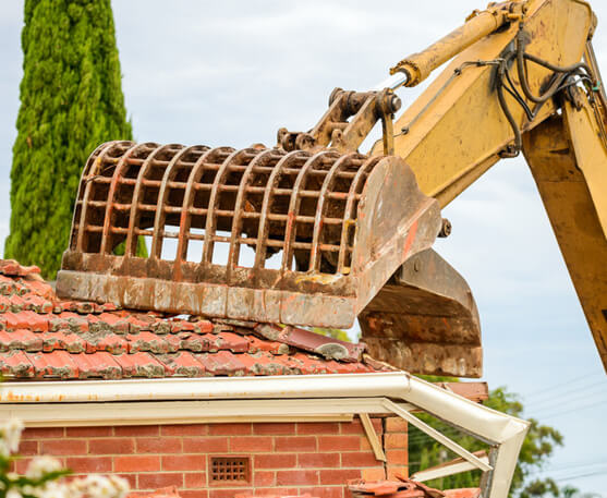 DN Roof Tiling & Restoration - image of excavator tearing down an old house roof