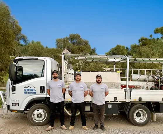 DN Roofing & Restoration homepage image of a re-roofing project, an image of Dan and the work crew standing if front of one of their work trucks with their hands behind their backs.